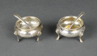 A pair of Victorian silver table salts with repousse decoration on pad feet together with 2 spoons 120 grams 