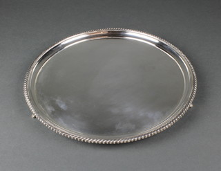 A circular silver salver with gadrooned rim on shell feet, Sheffield 1934 820 grams 