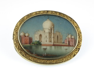 A 19th Century gold coloured oval brooch with painted Indian miniature scene of a temple 