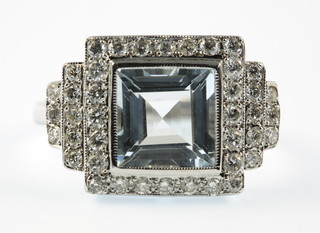 An 18ct white gold Art Deco style aquamarine and diamond cluster ring, with a stepped mount, size O 