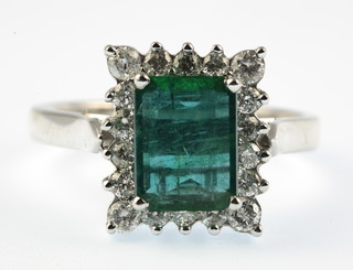 A 14ct white gold emerald and diamond cluster ring, the rectangular centre stone approx 2ct surrounded by brilliant cut diamonds 0.5ct, size P 