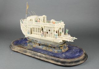 A late 19th Century ivory model of a barge with pierced panel decoration and crew, on a raised silk work plinth under a glass dome 17"  
