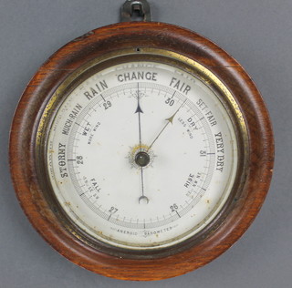 An aneroid barometer with paper dial, contained in a circular turned oak case 7"