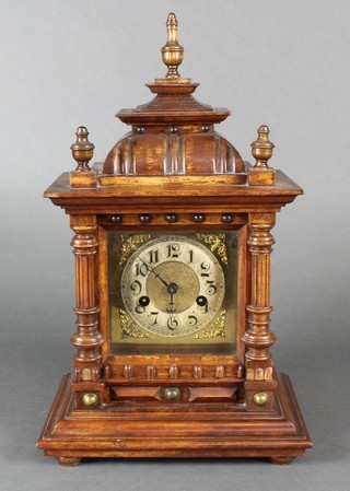 A 19th Century Continental striking bracket clock with square dial, silvered chapter ring and Arabic numerals contained in a carved walnut case by the Hamburg American Clock Co. 