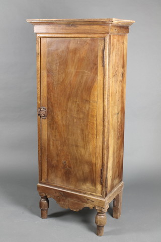 A Continental pine cabinet with moulded cornice, the shelved interior enclosed by a panelled door, raised on turned supports 59"h x 25"w x 16"d 