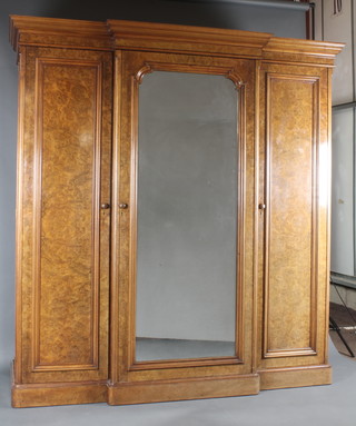 A handsome Victorian figured walnut breakfront triple wardrobe with moulded cornice, the centre section fitted 5 trays above 3 long drawers with brass swan neck drop handles and enclosed by arched panelled mirrored door, flanked by a pair of wardrobes one with hanging shelf and drawer to base, the other fitted 6 brass and mahogany double sided coat hangers and a commode compartment, 87"h x 80"w x 24"d 