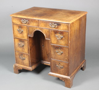 A Queen Anne style walnut kneehole pedestal dressing table, feather and crossbanded with quarter veneered top, fitted 2 short above 6 short drawers and having a cupboard to pedestal, raised on bracket feet 30"h x 31"w x 20"d