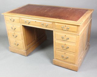 A light oak kneehole desk with inset leather writing surface above 1 long and 2 short drawers, raised on a platform base 30"h x 54"w x 30"d