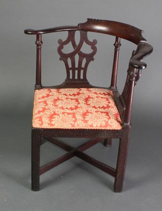 A Georgian oak corner chair with pierced vase shaped slat back and upholstered seat raised on square supports with X framed stretcher 