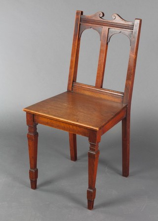 An Art Nouveau mahogany stick and rail back carver chair with solid seat, raised on square tapered supports 
