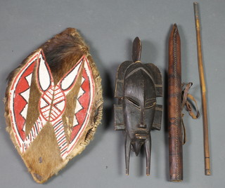 A carved African wall mask 17", an oval hide shield 21", an arrow and quiver 