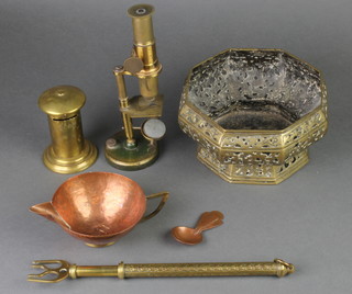 A brass single pillar students field microscope, an Eastern octagonal pierced brass bowl, a brass money box in the form of a pillar box, brass expanding toast fork, planished copper and brass cream jug and a caddy spoon