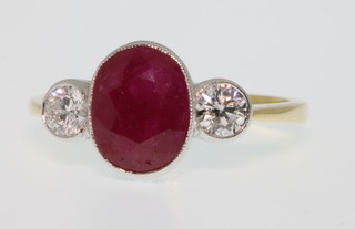 An 18ct white gold ruby and diamond ring, the oval ruby approx. 2.35ct, flanked by 2 brilliant cut diamond approx 0.42ct, size O