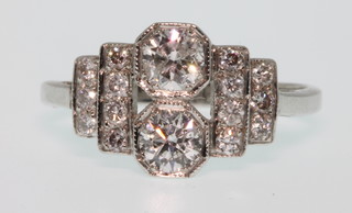 An 18ct white gold Art Deco style ring comprising 2 brilliants flanked by 7 brilliants to each shoulder, approx 0.95ct, size R 1/2