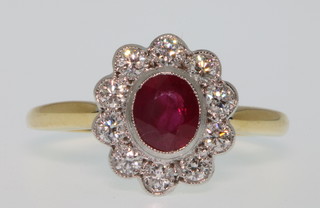 An 18ct yellow gold ruby and diamond cluster ring, the oval ruby surrounded by 10 brilliants size M 1/2