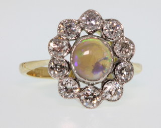 An 18ct yellow gold opal and diamond cluster ring, the oval centre opal surrounded by 10 brilliant cut diamonds, approx 0.9ct, size M