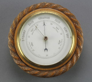 An aneroid barometer with enamelled dial contained in a carved oak frame with rope decoration 9 1/2" 