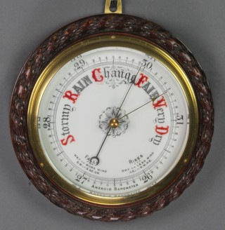 An aneroid barometer with enamelled dial contained in a carved oak case 12" 