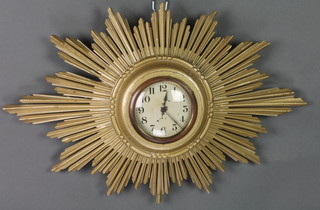 A 1930's timepiece with painted dial and Arabic numerals, contained in a carved gilt wood sunburst case and having a radio controlled battery operated movement 