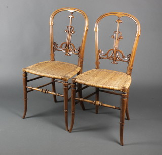 A pair of Victorian carved and pierced walnut bedroom chairs with slat backs and woven rush seats, raised on turned supports