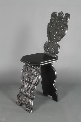 A 17th Century style Continental carved and ebonised hall chair with shield shaped back and solid seat 