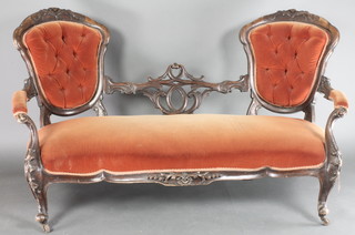 A Victorian carved and pierced mahogany show frame settee with pierced mid rail upholstered in orange buttoned dralon, on cabriole supports 