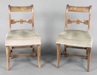 A pair of Georgian mahogany bar back dining chairs with carved mid rails and upholstered seats, raised on outswept supports 