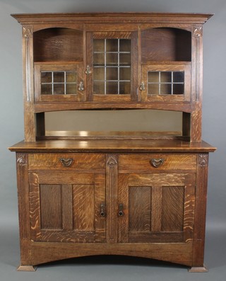 A Liberty's style Art Nouveau oak dresser, the raised back with moulded cornice fitted niches and cupboard enclosed by lead glazed panelled doors above a mirrored niche, the base fitted 2 long drawers above a double cupboard, carved throughout 78"h x 62"w x 23"d 