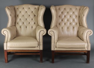 A handsome pair of Georgian style wing back armchairs upholstered in buttoned back white hide 