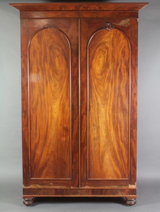 A Victorian mahogany Channel Islands wardrobe with moulded cornice enclosed by a pair of arched panelled doors, raised on bun feet 86"h x 57 1/2"w x 25"d