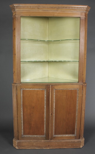 A 19th/20th Century pine corner cabinet, the upper section with moulded and dentil cornice above a niche, flanked by a pair of columns, the base fitted a cupboard enclosed by a panelled door 74"h x 40"w x 19"d 