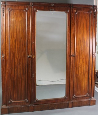 A Victorian mahogany triple wardrobe with moulded cornice, the centre section fitted 3 trays above 3 drawers and enclosed by a panelled door, flanked by a pair of cupboards enclosed by panelled doors 82"h x 72"w x 21"d 