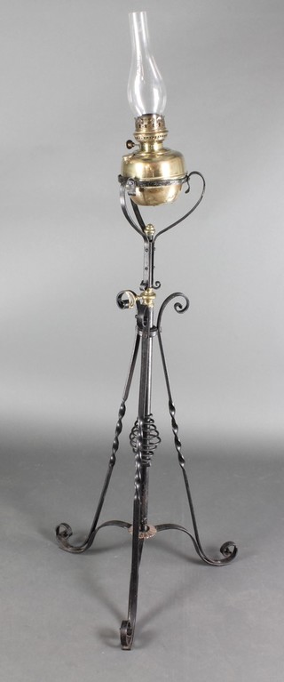 A Victorian wrought iron and brass adjustable oil lamp stand with clear glass shade