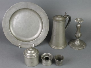 An 18th/19th Century circular pewter charger 12", a waisted pewter jug with glass base 8", a cylindrical pewter inkwell 2", a pewter measure 2", an Art Nouveau candlestick and a jar and cover 