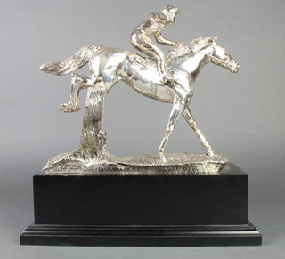 A silver filled trophy in the form of a jockey and horse jumping a fence on an ebony socle base 11" 