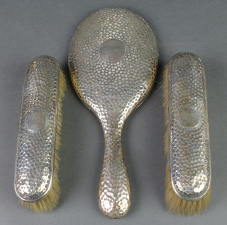 A silver hammer pattern brush set comprising oval hand mirror and 2 clothes brushes, London 1902
