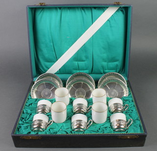 A cased white glazed 6 piece coffee set with repousse WMF holders and saucers, together with 4 white glazed spare liners