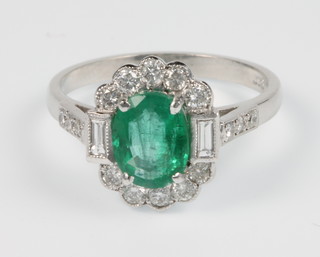 An 18ct white gold emerald and diamond Art Deco style ring, the centre stone approx 1.3ct, surrounded by diamonds approx. 0.5ct, size O 1.2