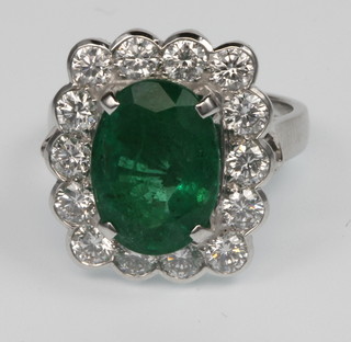 An 18ct white gold emerald and diamond cluster ring, the centre oval stone approx. 0.5ct surrounded by 14 brilliant cut diamonds approx. 1.8ct, size O, together with certificate 