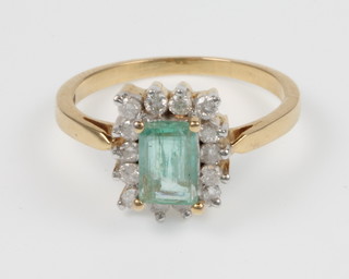 A 14ct yellow gold emerald and diamond surround dress ring, the central emerald approx. 2.50ct, the diamond surround approx. 0.5ct, size O