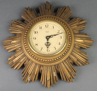 A 1950's Smith electric wall clock with paper dial and Arabic numerals contained in a carved wooden sunburst case 12" 
