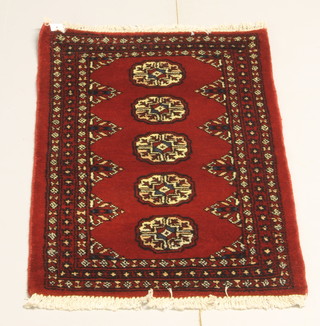 A red ground Bokhara style rug with 5 octagons to the centre 27" x 24" 