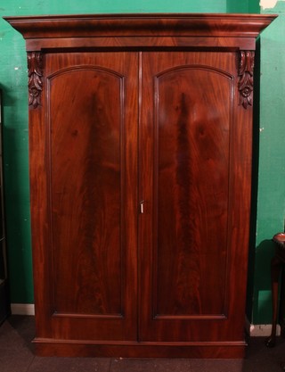 A Victorian mahogany Channel Islands wardrobe with moulded cornice, the interior fitted a shelf enclosed by a pair of arch panelled doors with vitruvian scrolls to the side and raised on a platform base 93 1/2"h x 61"w x 27"d