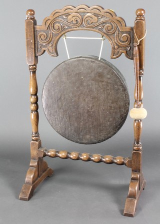 A 1920's bronze dinner gong raised on a carved oak stand 38"h x 24"w 