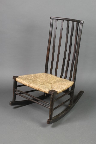 A Victorian Voisey style ebonised stick and bar back rocking chair with woven rush seat 