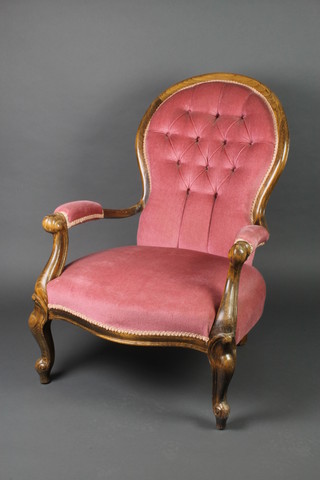 A Victorian style oak show frame arm chair upholstered in pink buttoned material, raised on cabriole supports 