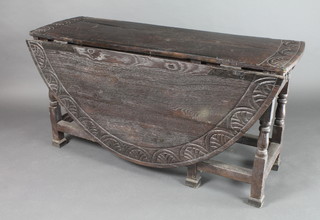 An 18th Century carved and weathered oak gateleg dining table on joined construction, fitted a frieze drawer, raised on turned and block supports 28"h x 17 1/2" when closed x 64" when extended