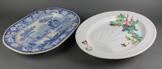 A Victorian blue and white meat plate, the floral border enclosing an extensive rural landscape 14" and an Edwardian polychrome floral ditto 