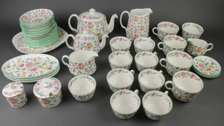 A Minton Haddon Hall tea and coffee set comprising 8 tea cups, 4 coffee cups, 8 saucers, a cream jug, milk jug, large preserve pot, small preserve pot, large milk jug, a breakfast teapot, a large teapot, slop bowl, sugar bowl, 3 small dishes, 3 oval plates, 2 large saucers, 8 tea plates and a sandwich plate 