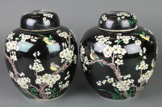 A pair of Chinese black ground ginger jars and covers decorated with birds amongst flowers 8" 